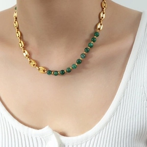 Close-up of asymmetrical vintage necklace with gold coffee bean links and green beads
