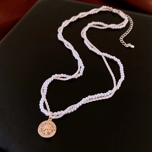 Dettaglio macro della collana a strati placcata oro con perle e pendente a stella vintage