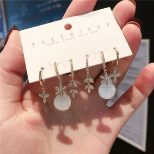 Macro view of a 6-piece gold earring set with white zircons and floral leaf charms