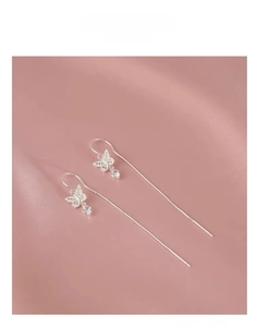 Macro shot of silver bow long tassel earrings with sparkling cubic zirconia on silk