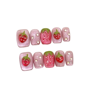 Pink cat eye press-on nails set with 3D strawberry and pearl accents on white background