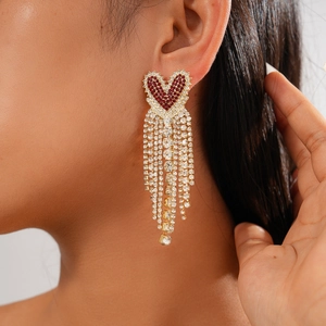 Close-up of heart-shaped earring with red rhinestones and silver needle fringe tassels
