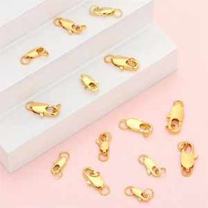 Vergoldete Karabinerverschlüsse auf weißen Stufen und rosa Hintergrund für DIY-Schmuck
