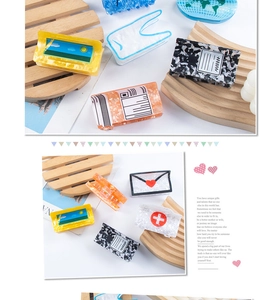 Close-up of colorful acrylic hair claws on a wooden tray with envelope and medical box patterns