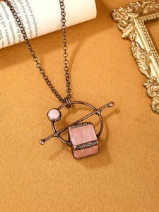 Detailed view of vintage rose quartz pendant with antique bronze frame on aged paper