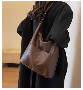 Detail view of large dark brown leather tote bag with soft texture and front pockets