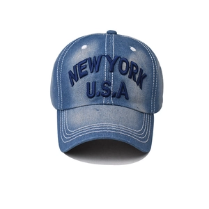 Detailed close-up of NEW YORK U.S.A blue embroidery on washed denim baseball cap texture