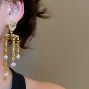 Vintage gold tassel earrings with teardrop zircon and white pearls on female model