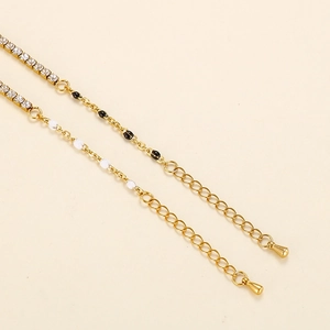 Macro detail of gold chain bracelet with rhinestones, colorful beads and drop pendant