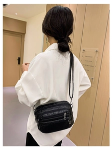 Détail d'un sac banane noir motif pierre avec fermetures éclair argentées sur un mannequin