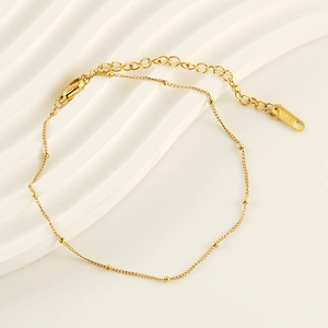 Close-up of gold stainless steel anklet with beads, lobster clasp and S.STEEL tag