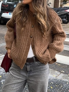 Detailed close-up of brown knit texture and button closure on long sleeve cardigan