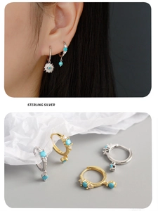 Detail of S925 sterling silver hoop earrings with turquoise stones and gold sun charms