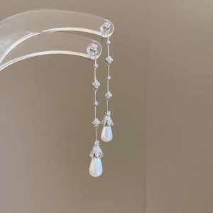 Detail of silver clover earrings with sparkling tassels and white teardrop pearls
