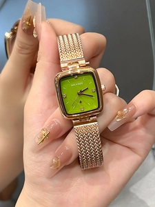 Detailed close-up of a square rose gold watch with a green dial and mesh strap
