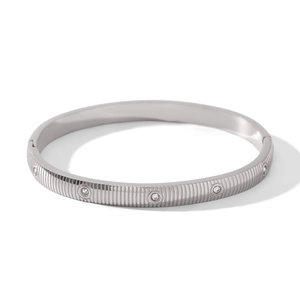 Detail view of silver stainless steel bangle with vertical stripes and inlaid zircons