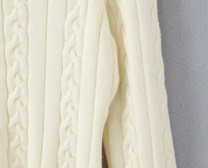Détail de la texture en maille torsadée crème et des coutures de haute qualité