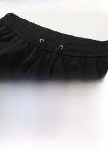 Detail of men's black sports pants featuring elastic waist with gold tipped drawstrings