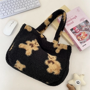 Close-up of black fleece tote bag featuring cute beige bear pattern on a desk