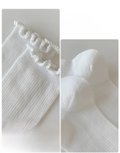 Detail of ruffle trim socks showing the elastic cuff and reinforced non-slip heel design
