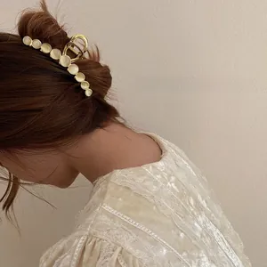 Detail of elegant gold metal hair claw clip with cat eye stones on a ponytail style