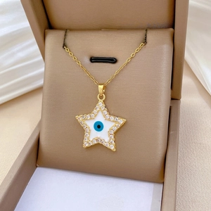 Detailed shot of a gold star necklace with zircon pavé and blue evil eye enamel center
