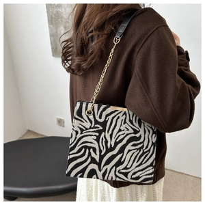 Detail of zebra pattern fabric and gold chain strap on stylish crossbody bag