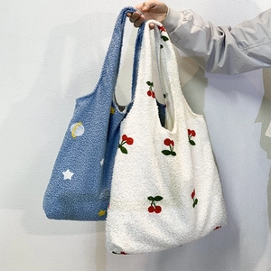 Close-up of soft faux shearling tote bags with cherry and star embroidery detail
