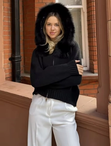 Close-up of fluffy faux fur collar on black knitted jacket with a cozy outdoor texture