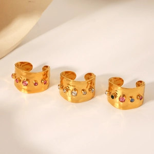 Dettaglio di anelli vintage placcati oro con zirconi colorati e trama in metallo martellato