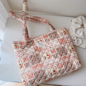 Close-up of quilted floral patchwork tote bag showing detailed fabric texture and label