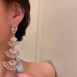Close-up of luxury tiered fan-shaped earrings with purple crystals on a female model