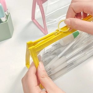 Transparent yellow minimalist pencil case with zipper closure being held by hand