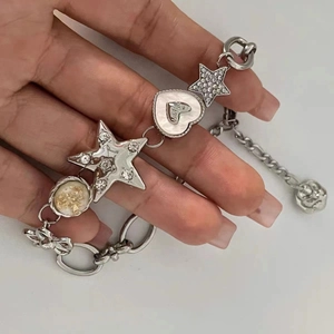 Silver metallic bracelet with star and heart charms, featuring shell and crystal details