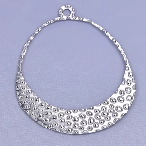 Macro shot of silver crescent pendant with hammered texture and polished metal finish