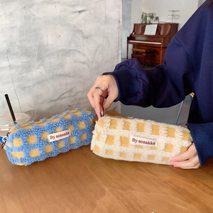 Detail view of waffle knit plush pencil pouches in blue and yellow checkered patterns