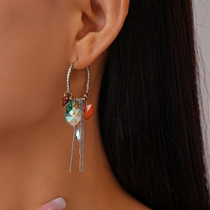 Detail of silver hoop earring with red heart crystal and long metal fringe tassels