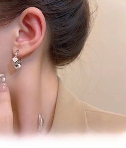 Detail view of elegant silver triple heart drop earrings worn on model ear