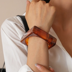 Macro detail of geometric amber resin square bangle on model with white shirt