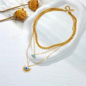 Detail of gold layered stainless steel necklace with blue evil eye and sun pendants