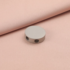 Macro detail of a 20mm matte silver stainless steel double-hole bead on pink fabric