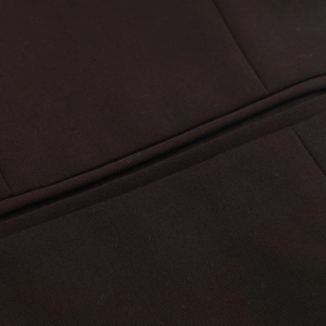Gros plan détaillé sur la texture du tissu sergé marron foncé et les coutures d'un costume