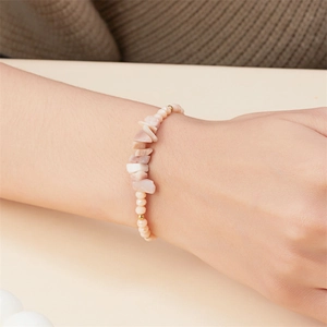 Detail eines handgefertigten Armbands mit unregelmäßigen rosa Kristallen und Goldperlen