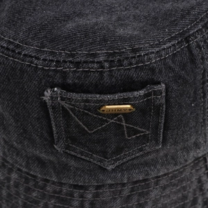 Détail d'un bob en jean noir délavé avec une petite poche latérale et un logo en métal doré