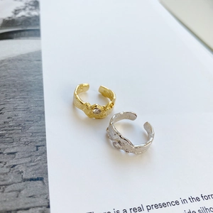 Macro detail of gold and silver S925 rings with hammered texture and zircon on white book