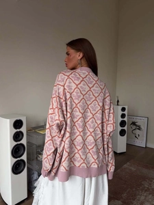 Oversized pink and white diamond pattern knitted cardigan for women in a cozy room