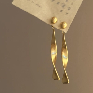 Artistic matte gold twisted ribbon dangle earrings for women with elegant spiral drop design