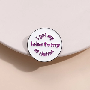 Round enamel brooch with I got my lobotomy at claires text and black metal edge