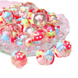 Colorful acrylic beads with mushroom and strawberry patterns in a glass dish for DIY craft