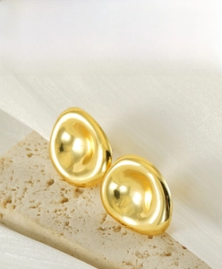 Detailed view of irregular 18K gold plated concave earrings on premium textured stone